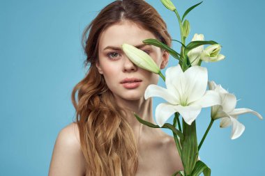 Mavi arka planda beyaz çiçekli bir kız. Kızıl saç portresi modeli.