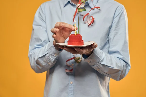 Um homem segurando um bolo em um prato e uma vela de cima fundo isolado — Fotografia de Stock