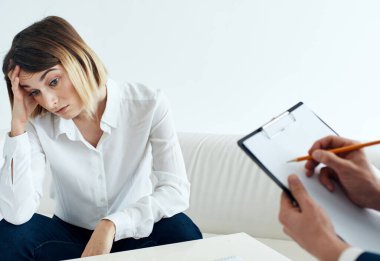 Gömlekli bir iş kadını kanepeye oturur ve adam iş modelini belgeler.