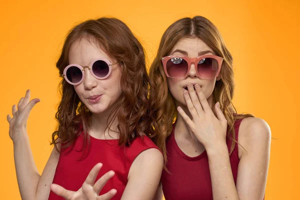 Alegre mamá e hija usando gafas de sol estilo de vida amistad familia amarillo fondo estudio —  Fotos de Stock