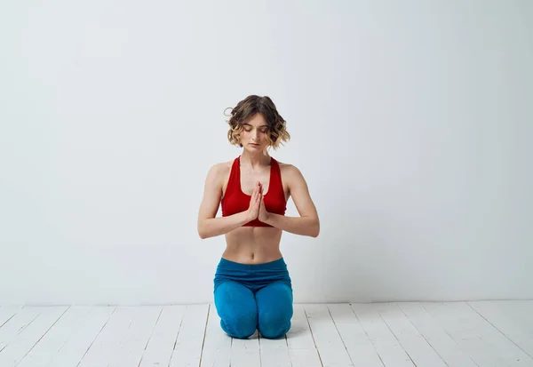 Жінка сидить на світлій підлозі в приміщенні з руками, що з'єднують асан йоги для релаксації — стокове фото