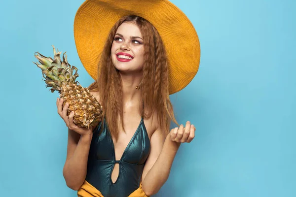 Kvinna i strand hatt ananas innehav baddräkt exotiska frukter blå bakgrund semester — Stockfoto