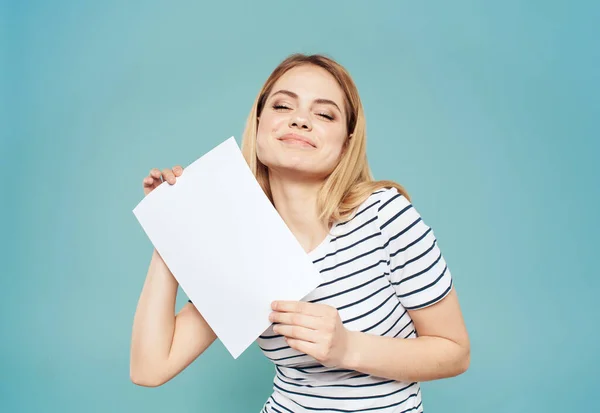 Mulher loira emocional com uma folha de papel branca em suas mãos em um fundo azul — Fotografia de Stock