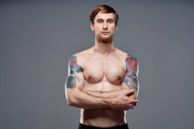 Kollarında dövmeleri olan, gövdesi şişmiş, vücut geliştiren bir adam.