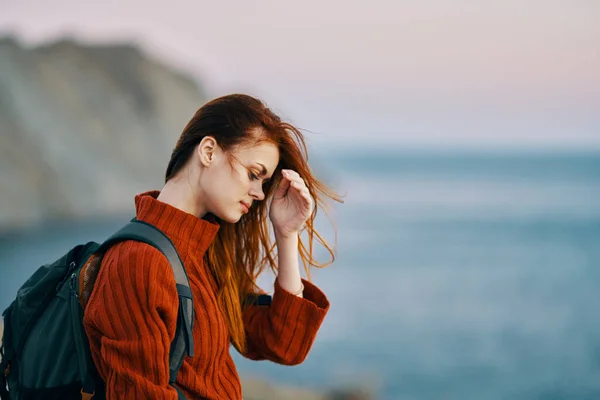 Bella donna in un maglione con uno zaino sulla schiena e mare montagne natura aria fresca — Foto Stock