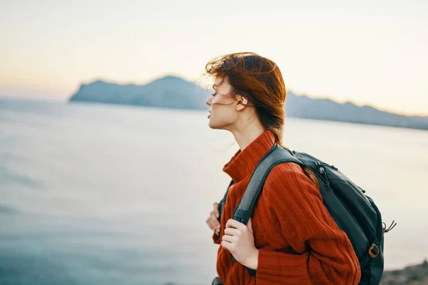 Un viaggiatore in montagna con uno zaino sulla schiena va di lato e il mare è vicino — Foto Stock