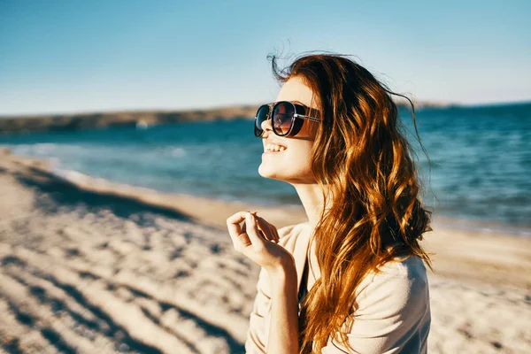 Vista laterale della donna dai capelli rossi modello in camicia e occhiali vicino al mare sulla spiaggia — Foto Stock