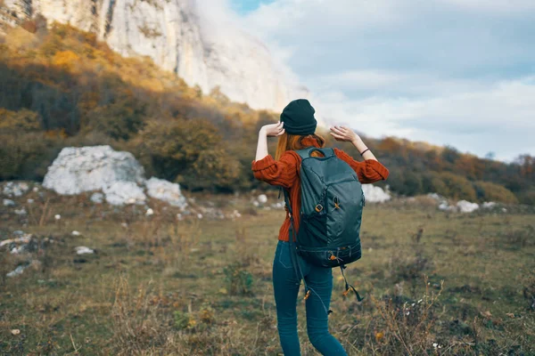 Ένας ταξιδιώτης σε ένα πουλόβερ με ένα σακίδιο στην πλάτη της ζεστό καπέλο τοπίο φθινόπωρο βουνά — Φωτογραφία Αρχείου