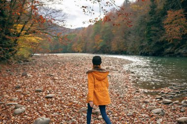 Sonbahar ormanı nehrindeki neşeli kadın temiz hava.