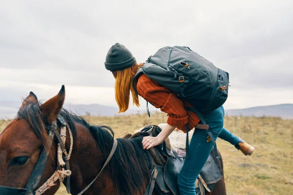 woman hiker with backpack rides a horse travel lifestyle