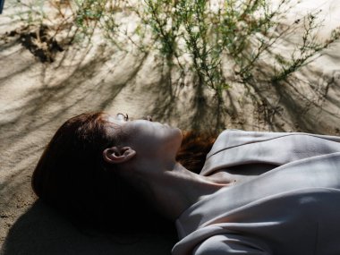 Kadın kumlara uzanıp yaz güneşini dinlendiriyor.