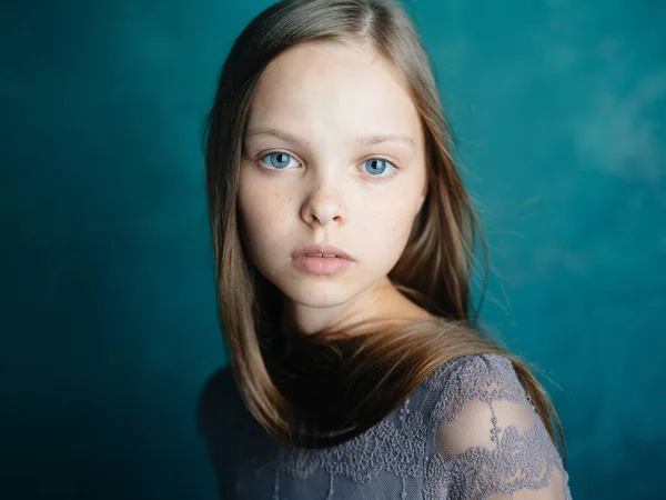 모델의 모습을 클로즈업 한 푸른 배경 위에 회색 드레스를 입은 아름다운 어린 소녀의 모습 — 스톡 사진