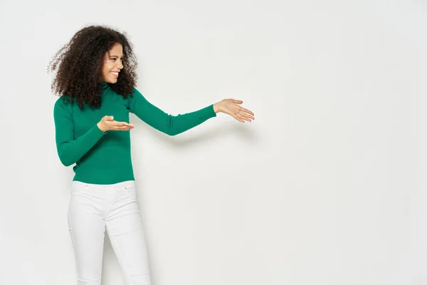 Vrouw met krullend haar en groene trui emoties gebaren handen studio — Stockfoto