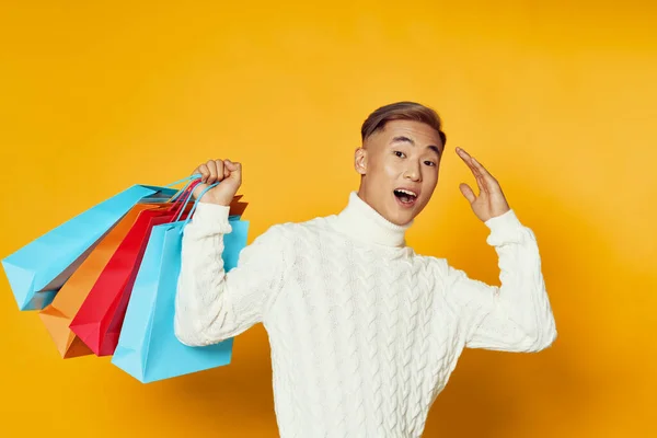 Asiatico uomo inverno maglione shopping regali giallo sfondo gioia — Foto Stock