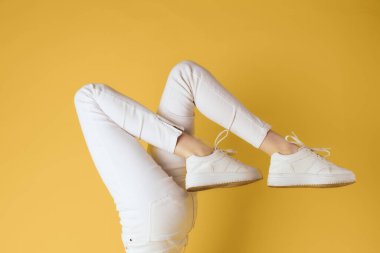 Kadın bacakları beyaz kot pantolonlar moda sarı arka plan görüntüsü