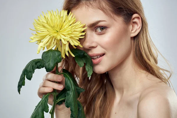 Portret pięknej kobiety z żółtym kwiatem na jasnym tle czarujący uśmiech model rude włosy — Zdjęcie stockowe