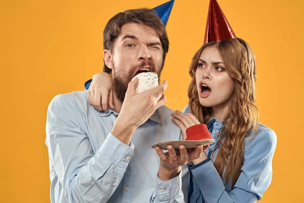 Birthday party mężczyzna i kobieta zabawy żółty tło czapka wakacje — Zdjęcie stockowe