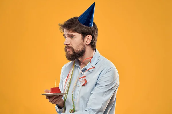 Chico con un pastel en un plato en un fondo amarillo vacaciones vela vista recortada — Foto de Stock