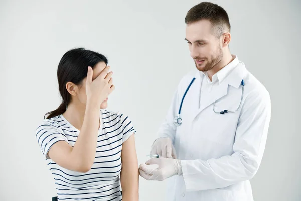 Beyaz önlüklü erkek doktor hastalara bir iğne enjekte ediyor. Kol aşısı. — Stok fotoğraf
