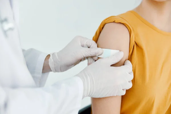 Un médico en un hospital sella una herida en el hombro de una mujer vacunación covid —  Fotos de Stock