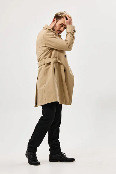Hombre guapo en abrigo beige aspecto atractivo estudio estilo moderno fondo de luz — Foto de Stock