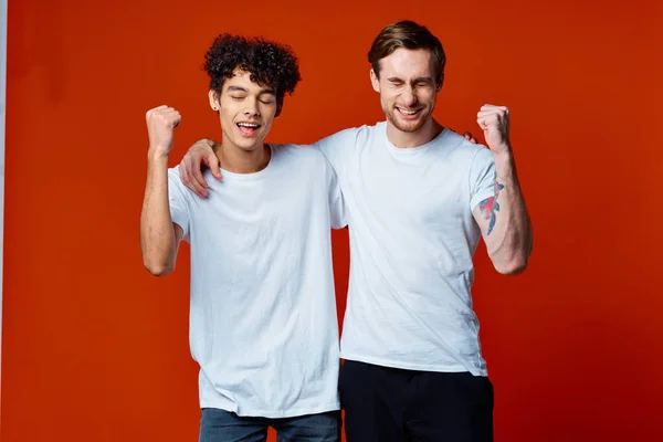 Dos amigos alegres con camisetas blancas están de pie junto a las emociones del equipo — Foto de Stock