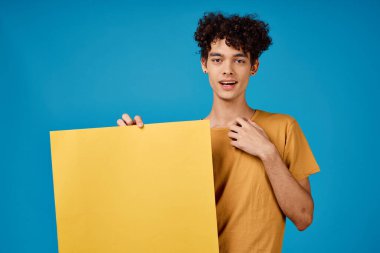 Sarı tişörtlü adam afiş modeli, mavi arka plan reklamı.