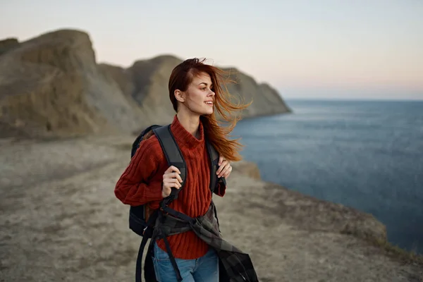 Viaggiatore dai capelli rossi con uno zaino appoggiato sulla spiaggia vicino al mare in montagna autunno — Foto Stock