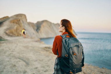 Sırt çantalı bir gezgin deniz kenarındaki dağlarda dinleniyor.