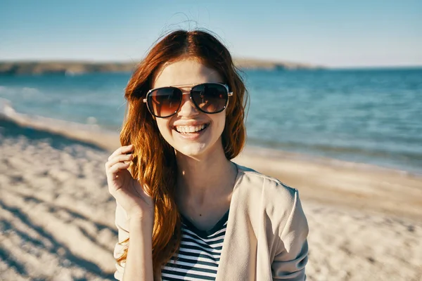 Mulher feliz na praia perto do mar nas montanhas óculos no rosto vermelho cabelo modelo paisagem — Fotografia de Stock