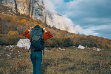 Sırt çantalı kadın dağlarda dinleniyor doğada ve sonbahar sarısı yapraklar üzerinde
