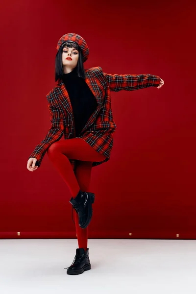Brune sexy en leggings de manteau gesticulant avec les mains sur fond rouge à l'intérieur — Photo