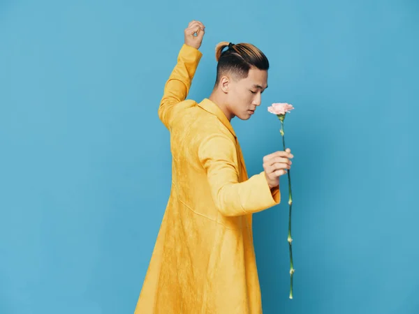 Um homem de casaco amarelo com uma flor está dançando sobre um fundo azul — Fotografia de Stock