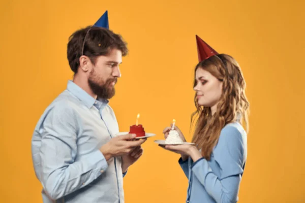 Homme et femme heureux avec gâteau d'anniversaire sur fond jaune — Photo