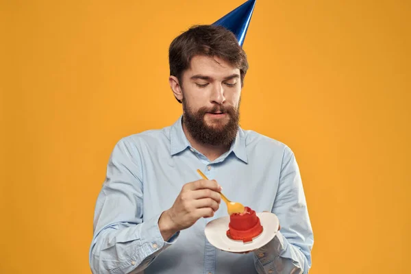Человек с праздничным тортом в руках на желтом фоне праздничного десерта — стоковое фото