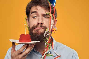 Elinde doğum günü pastası ve mumuyla şapkalı bir çocuk.