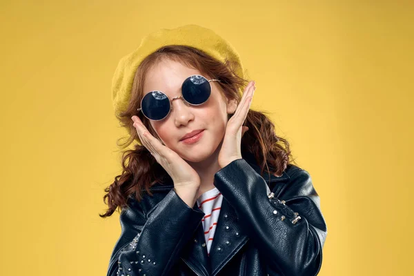Wesoła dziewczynka w okularach przeciwsłonecznych i kapelusz styl życia studio żółty tło moda — Zdjęcie stockowe