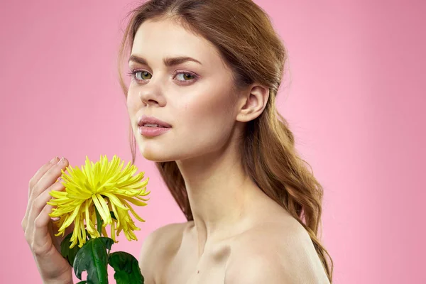 Retrato de una mujer con flores amarillas sobre un fondo rosa Maquillaje en la cara — Foto de Stock