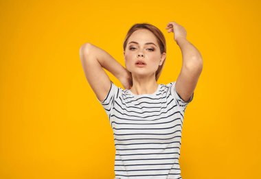 Sarı arka planda çizgili tişörtlü, duygusal sarışın kadın portresi.