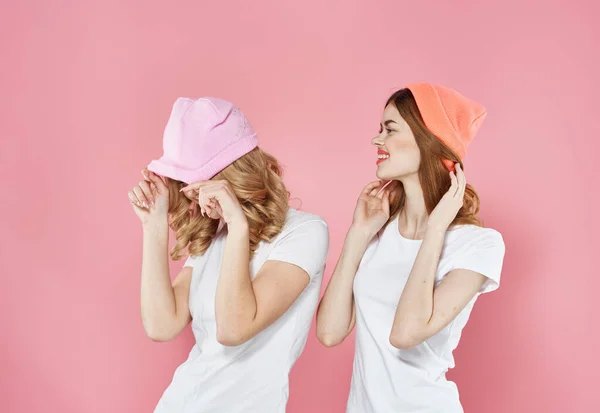 Mulheres glamourosas alegres abraços roupas na moda estúdio amizade rosa fundo — Fotografia de Stock