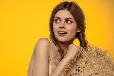 Hasır şapkalı güzel kadın. Çekici görünüyor. Sarı arka plan.