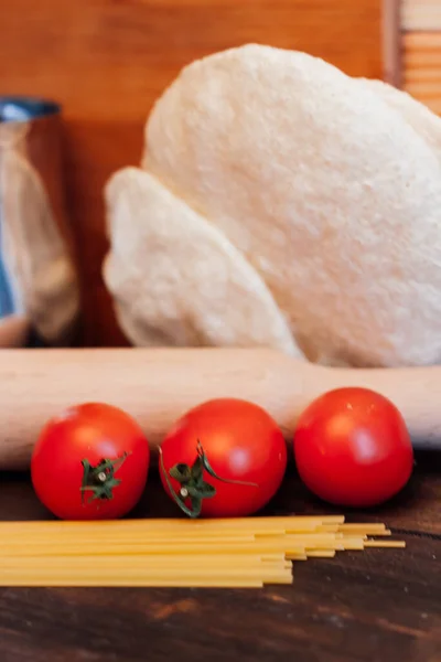 Pasta cosparsa sul tavolo pomodori attraverso la cucina italiana — Foto Stock