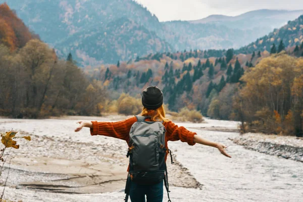 Gelukkig reiziger gebaar met haar handen op de oever van de rivier in de bergen — Stockfoto