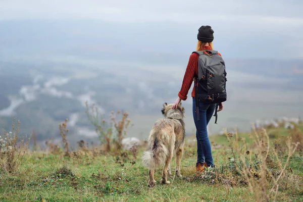 Жінка ходить з рюкзаком з собакою в горах подорожує дружба — стокове фото
