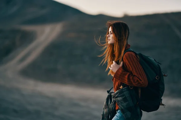 Turista donna con uno zaino sulla schiena che riposa in montagna e la strada in lontananza — Foto Stock