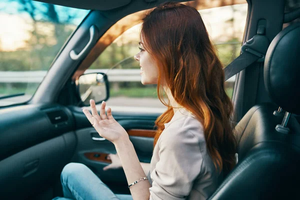 Mujer feliz compañero de viaje en el asiento delantero de un coche gesto con las manos hacia atrás ver — Foto de Stock