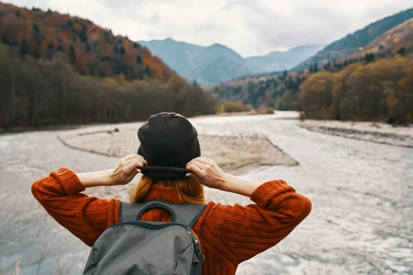 Viaggiatore donna in vacanza in montagna nella natura vicino al fiume si tiene per mano dietro la testa — Foto Stock