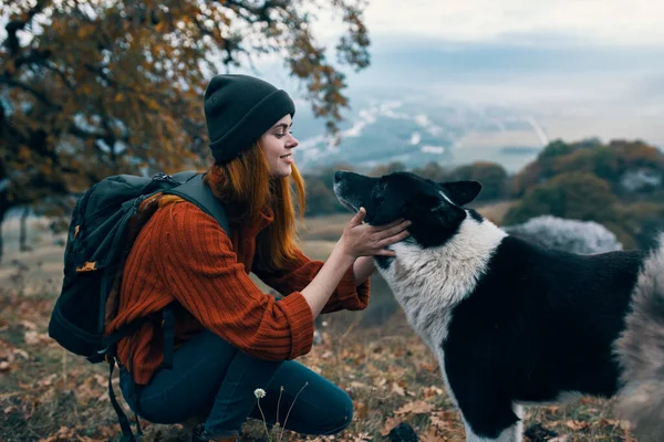 Donna con zaino in natura gioca con il cane nel paesaggio montano — Foto Stock