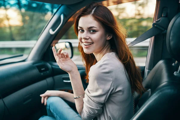 Boldog nő utazó társa az első ülésen egy autó gesztikuláló kezét hátra néző — Stock Fotó