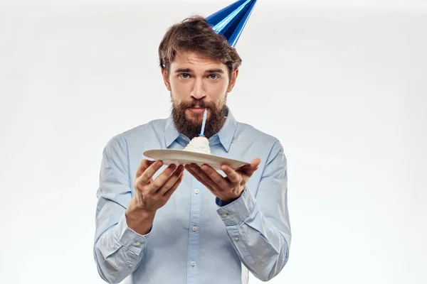 Un hombre con barba sostiene un pastel en su mano sobre un fondo claro cumpleaños — Foto de Stock